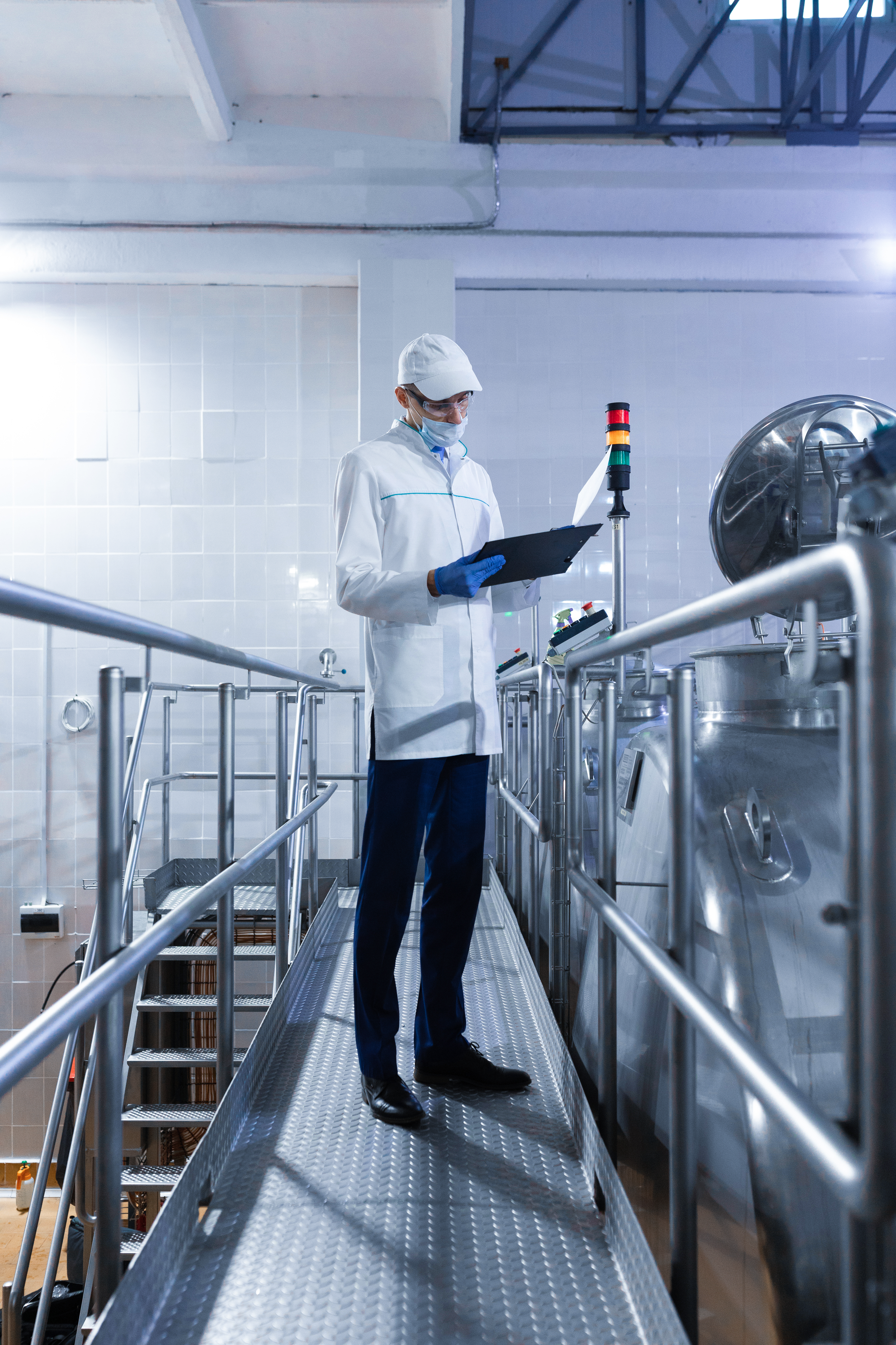 technologist inspecting production line while standing at department of dairy factory